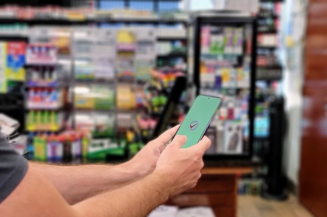 Hand holding a mobile phone in a convenience store.